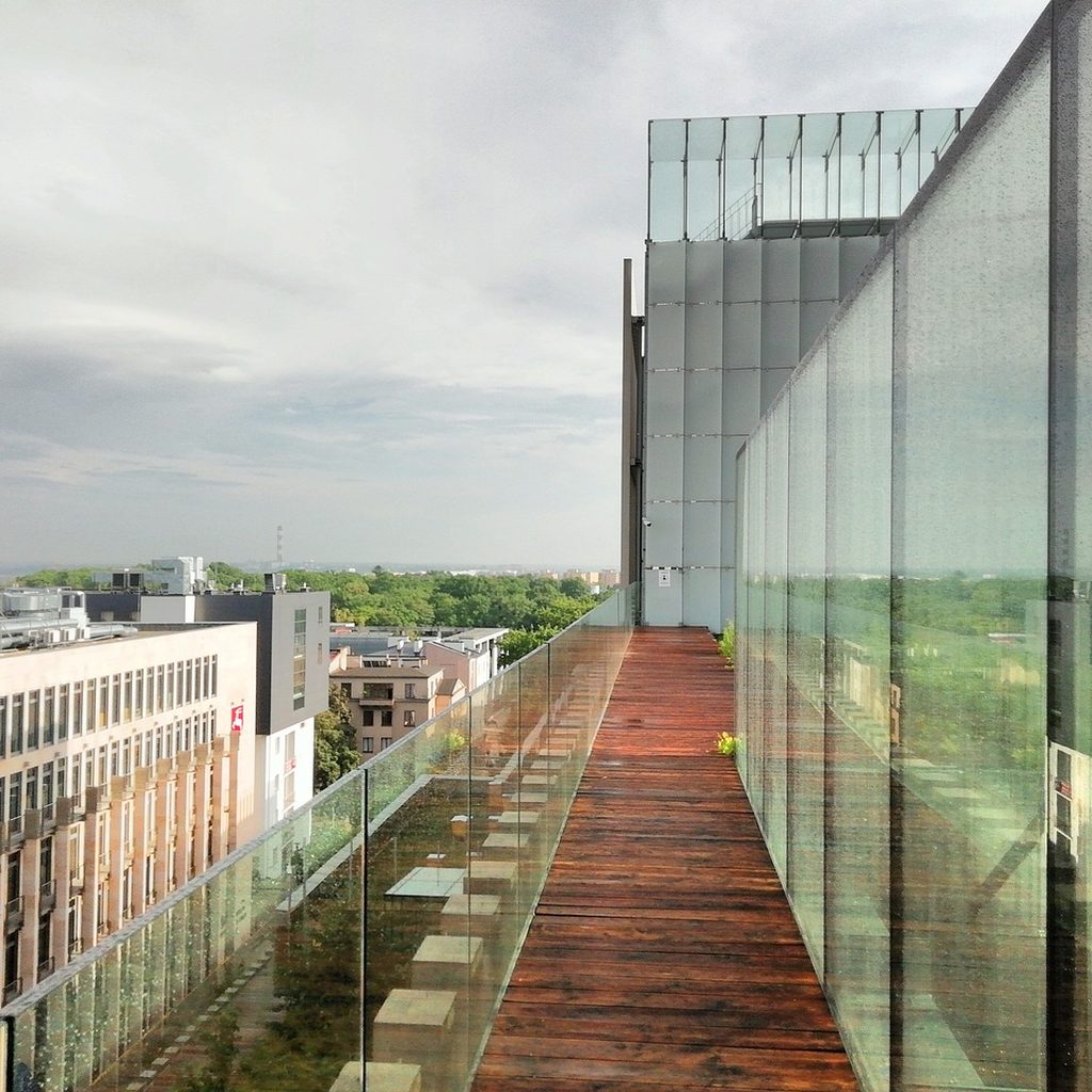 Glass-walled building with a planted rooftop walkway