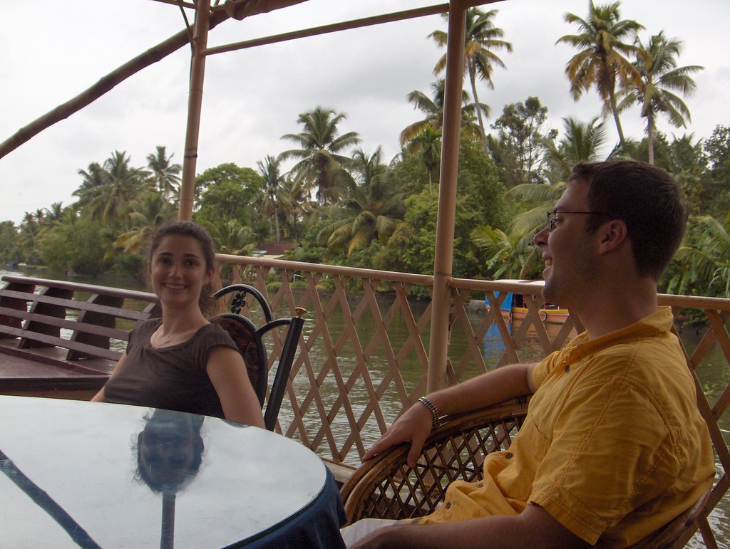 Two people talking over a table on a shaded veranda