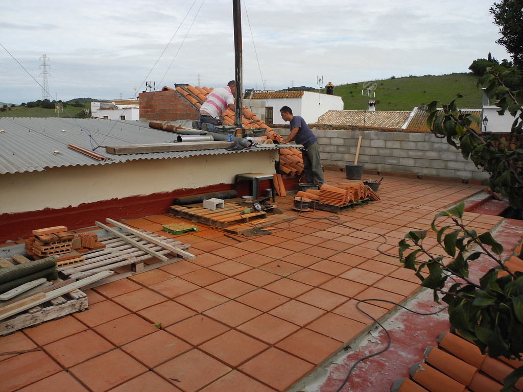Workers laying clay tiles on a flat roof terrace